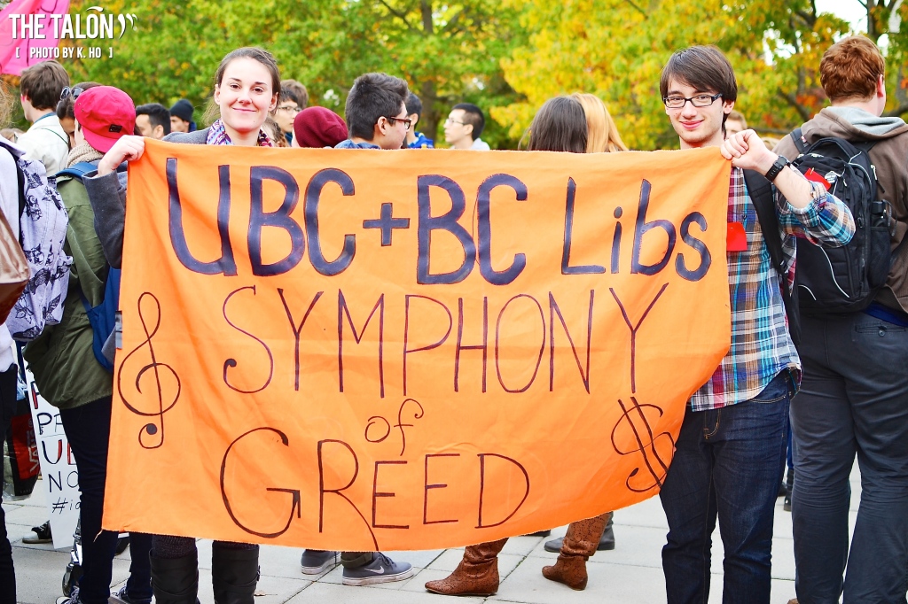 Students hold sign reading "UBC + BC Libs: Symphony of Greed"