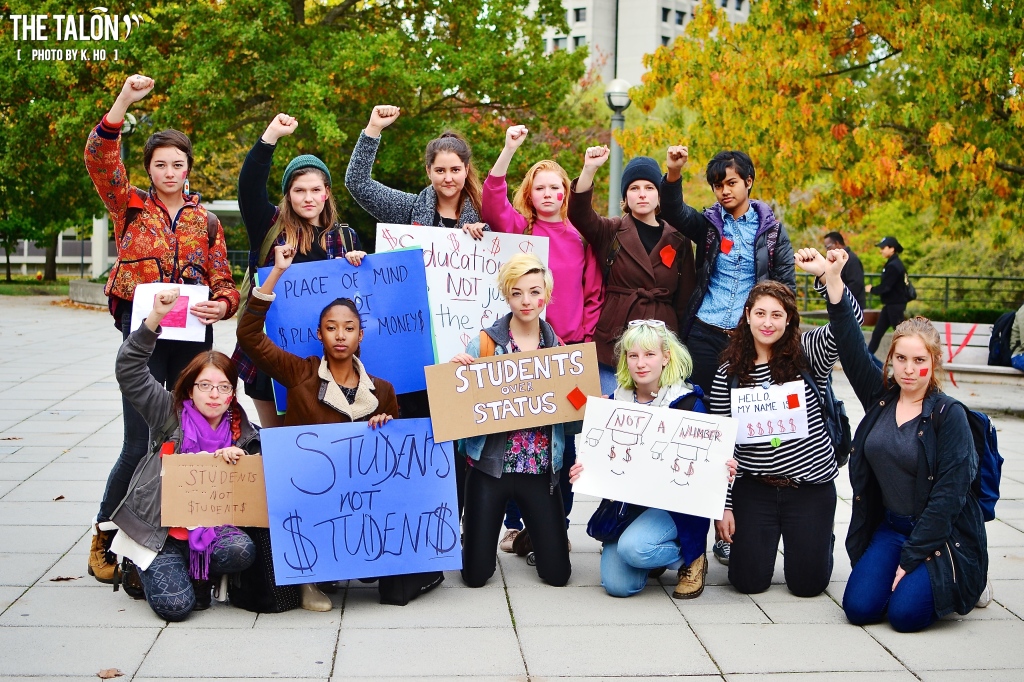 Students from the GRSJ Undergraduate Students' Association hold a variety of creative protest signs.